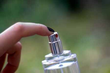 Spraying perfume from a glass bottle. Selective focus, natural green background.の写真素材