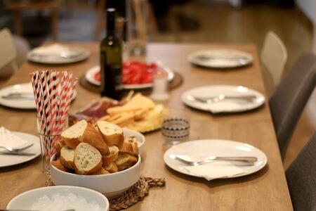 Table set for dinner party with plates, bread, ice, paper straws and spread. Selective focus.の写真素材