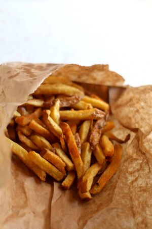 French fries in a brown paper bag. Selective focus.