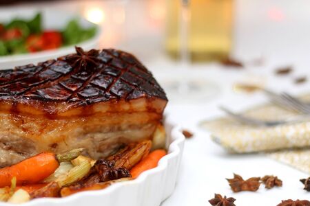 Pork belly roast and roasted vegetables on a holiday table. Selective focus.の写真素材