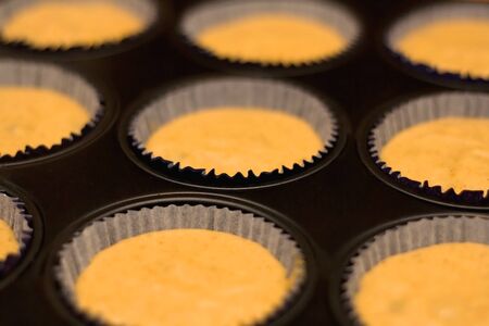 Cupcake mixture in a tray, ready for baking. Selective focus.の写真素材