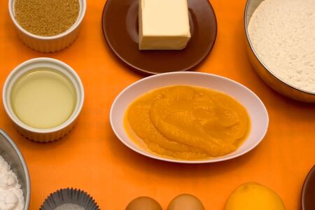 Cupcake ingredients on a table: pumpkin puree, flour, eggs, butter, sugar and nuts. Selective focus.の写真素材