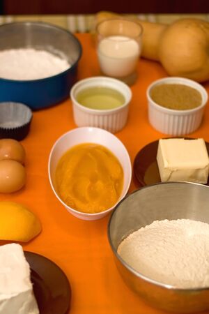 Cupcake ingredients on a table: pumpkin puree, flour, eggs, butter, sugar and nuts. Selective focus.の写真素材