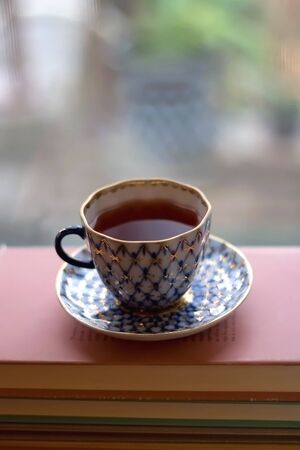 Tea in a vintage porcelain cup on stack of pastel colored books. Selective focus.の写真素材