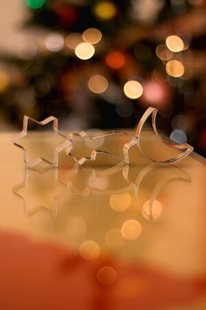 Cookie cutters shaped like moon and stars. Christmas tree in the background. Selective focus.の写真素材