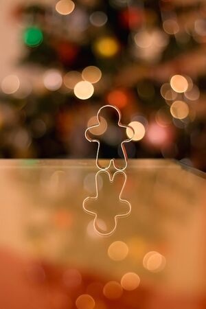 Cookie cutter shaped like gingerbread man. Christmas tree in the background. Selective focus.の写真素材