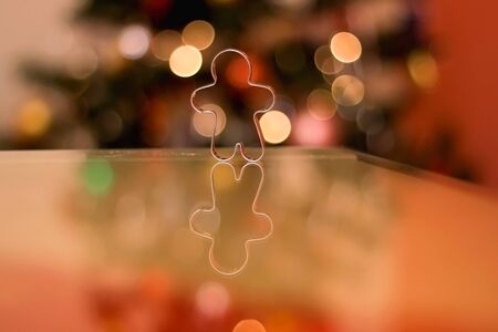Cookie cutter shaped like gingerbread man. Christmas tree in the background. Selective focus.の写真素材