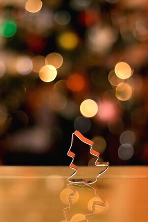 Cookie cutter shaped like Christmas tree. Christmas tree in the background. Selective focus.の写真素材