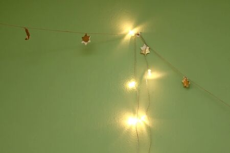 Handmade garland with white and golden stars and moons. Selective focus, green background.