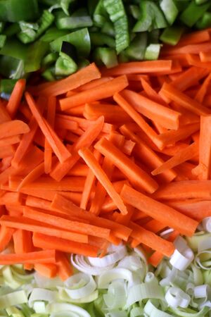 Chopped carrots, leek and green peppers on a cutting board. Top view.の写真素材