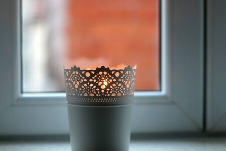 Candle light holder on a window. Selective focus.