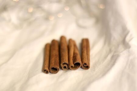 Cinnamon sticks on white background with bokeg lights. Selective focus.