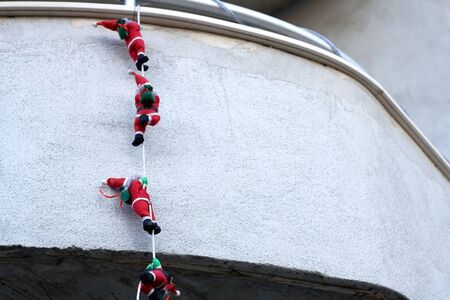 Outdoor Christmas decoration, climbing Santas, on a balcony. Selective focus.