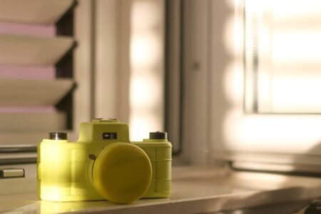 Yellow plastic film camera, illuminated by warm sunset light. Selective focus.