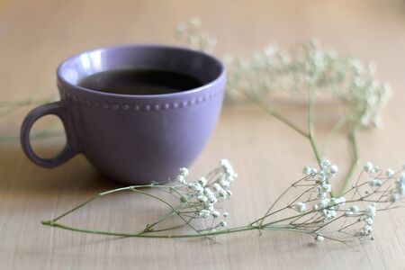 Cup of tea and gypsophila flowers on wooden table. Selective focus.