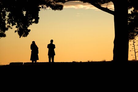 Silhouettes of unrecognizable people enjoying the sunset in Sustipan park in Split, Croatia.の写真素材