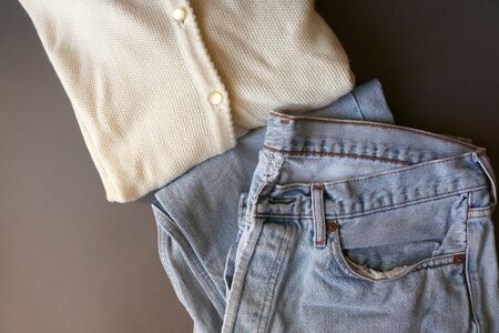Vintage white cardigan and light wash mom jeans. Top view, dark grey background.の写真素材