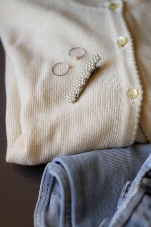 Vintage white cardigan, light wash mom jeans, floral hair beret and rings. Selective focus.
