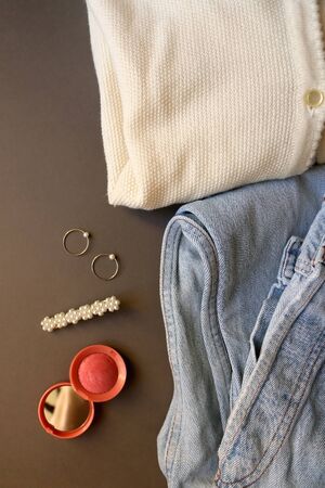Fashionable outfit with vintage jeans, white cardigan, pink blush, beret and rings. Top view.の写真素材
