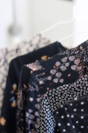 Black patterned dresses on a clothing rack. Selective focus.