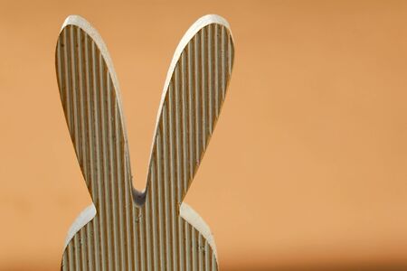 Wooden minimal Easter bunny decoration. Selective focus, pastel orange background.の写真素材