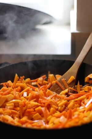 Stir frying carrot and pumpkin in a wok. Selective focus.の写真素材