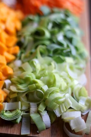 Chopped carrots, leek, red kuri squash and portobello mushroom on a wooden cutting board. Selective focus.の写真素材