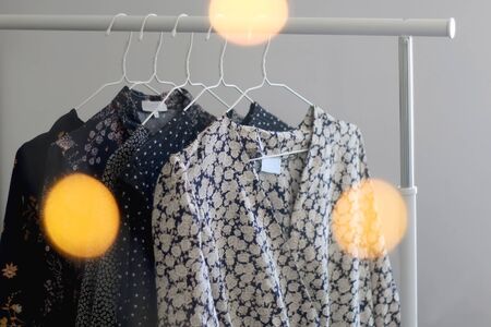 Collection of black floral dresses on a clothing rack. Selective focus, bokeh lights in the...