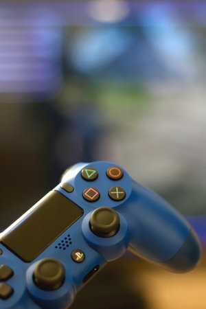 Split, Croatia - June 24, 2019: Blue Playstation gaming controller in front of a tv. Selective...