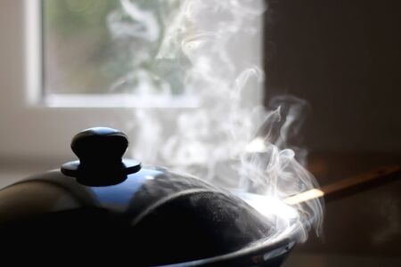 Wok with steam on the stove. Selective focus.