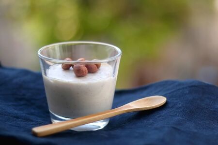 Glass of vanilla pudding with hazelnut topping and wooden spoon. Selective focus.の写真素材