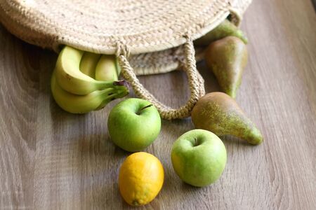 Apples, pears, bananas and lemon in a straw bag. Selective focus.