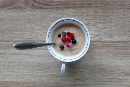 Cup of nice cream, made with frozen bananas, peanut butter and vegan milk. Frozen berries on the top. Flat lay.の写真素材
