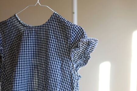 Top with gingham pattern on a clothing rack. Selective focus.