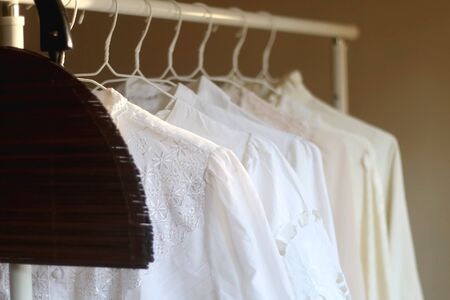 Vintage wooden bag and white blouses on a clothing rack. Selective focus.の写真素材