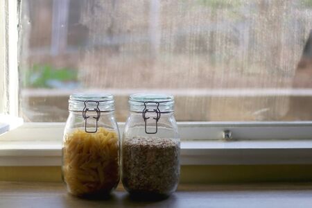 Jars with pasta and oats. Kitchen or pantry interior. Selective focus.