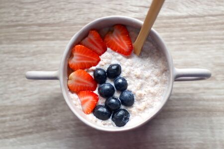 Bowl of rice and cinnamon vegan porridge with strawberry and blueberry topping. Top view.の写真素材