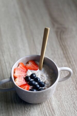 Bowl of rice and cinnamon vegan porridge with strawberry and blueberry topping. Selective focus.の写真素材