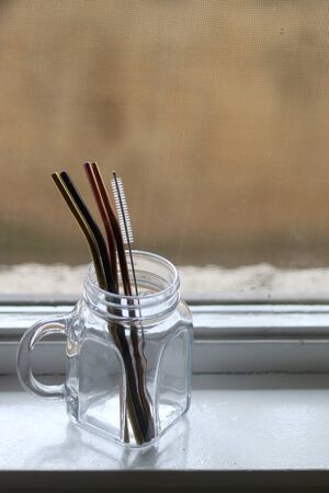 Reusable metal straws and cleaner in a glass jar. Selective focus.の写真素材