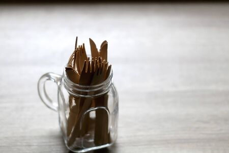 Glass jar with wooden forks and knifes on a table. Selective focus.
