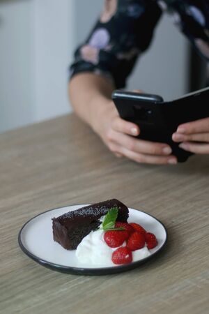 Unrecognizable person taking phone photo of a piece of cake. Selective focus.の写真素材
