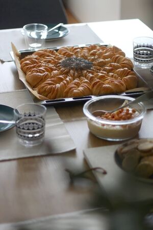 Various food served on a table: cake, homemade bread, crackers, hummus and strawberries. Vase with...