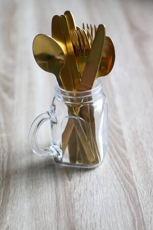 Gold colored cutlery in a mason jar. Selective focus.の写真素材