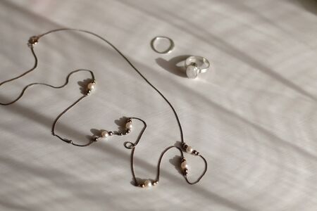 Silver jewelry on white background, illuminated by sunlight. Selective focus.の写真素材