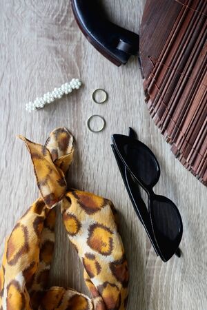 Fashionable and vintage accessories on a table: leopard print scarf, wooden handbag, cat eye...