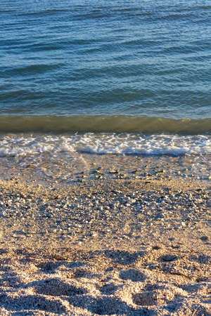 Gravel and sand on a beach at sunset. Close-up, selective focus.