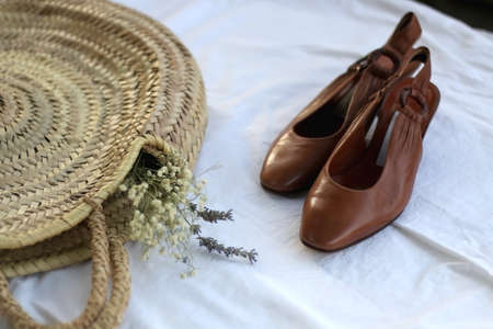 Wicker bag with flowers and brown vintage shoes. Selective focus.