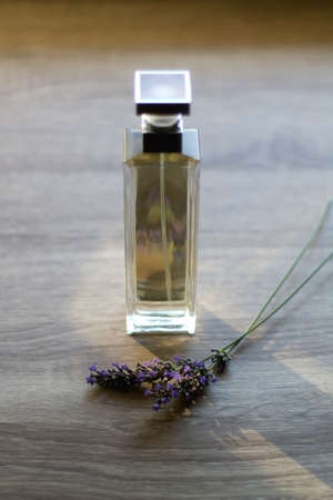 Bottle of perfume and lavender flower on wooden background. Selective focus.