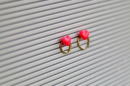 Gold wedding rings pinned with heart shaped pins on a bulletin board. Wedding concept. Selective focus.の写真素材