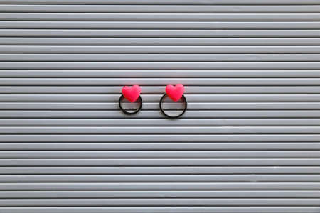 Gold wedding rings pinned with heart shaped pins on a bulletin board. Wedding concept. Flat lay.
